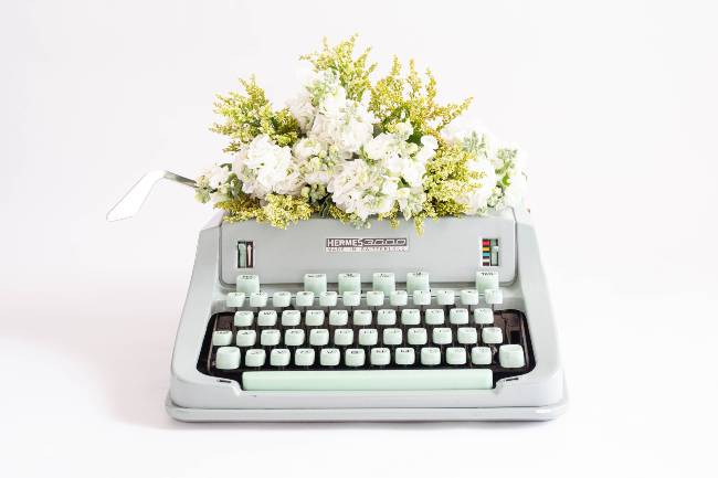 antigua máquina de escribir con florcitas en la parte de la hoja